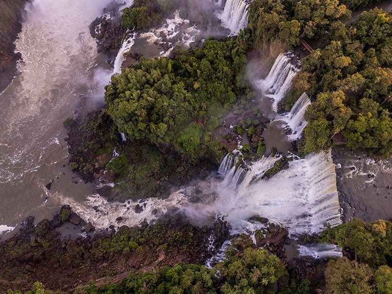 Vista aérea das Cataratas do Iguaçu, uma das maravilhas naturais de Foz do Iguaçu. As poderosas quedas d'água são cercadas por uma exuberante vegetação, criando um cenário impressionante e um dos principais destinos para passeios na cidade.