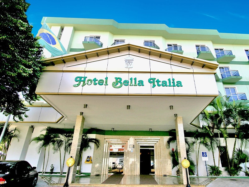 Fachada do Hotel Bella Italia em Foz do Iguaçu, mostrando a entrada principal com a placa do hotel e detalhes arquitetônicos elegantes.