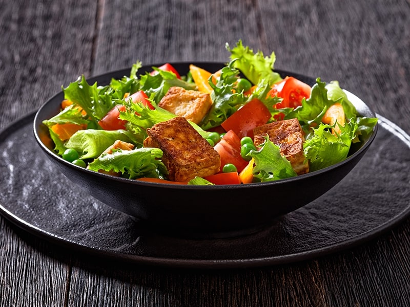 Salada fresca e colorida com alface, tomates, tofu grelhado, ervilhas e pimentões amarelos