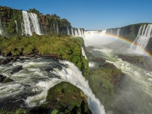 Vista panorâmica da Garganta do Diabo em Cataratas Del Iguazu, com várias quedas d'água impressionantes e um arco-íris formado pela névoa.