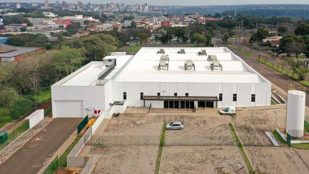 Infraestrutura do novo Mercado Municipal de Foz do Iguaçu, destacando o estacionamento, amplo espaço, paredes brancas.