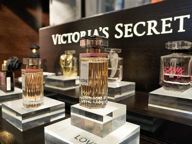 Exposição elegante de fragrâncias da Victoria’s Secret, destacando perfumes icônicos, em uma loja sofisticada em Ciudad del Este.