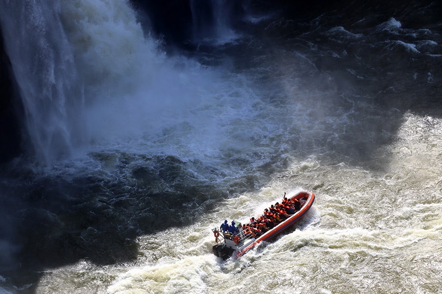 Barco do Macuco Safari se aproximando das quedas d'água das Cataratas do Iguaçu, proporcionando uma experiência emocionante para os visitantes.