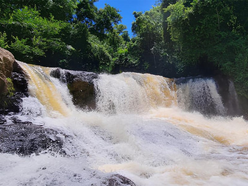 Uma cachoeira com vegetação verde a redor.